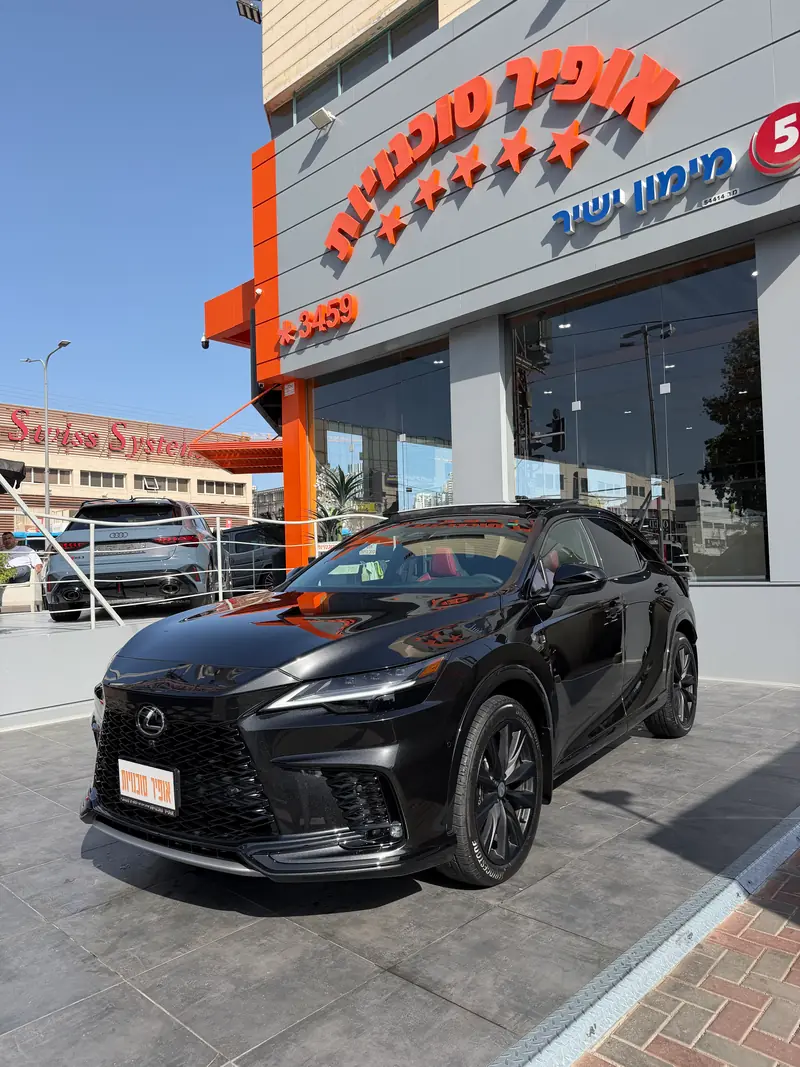 לקסוס RX 500h שחורה מול הבניין והשלט